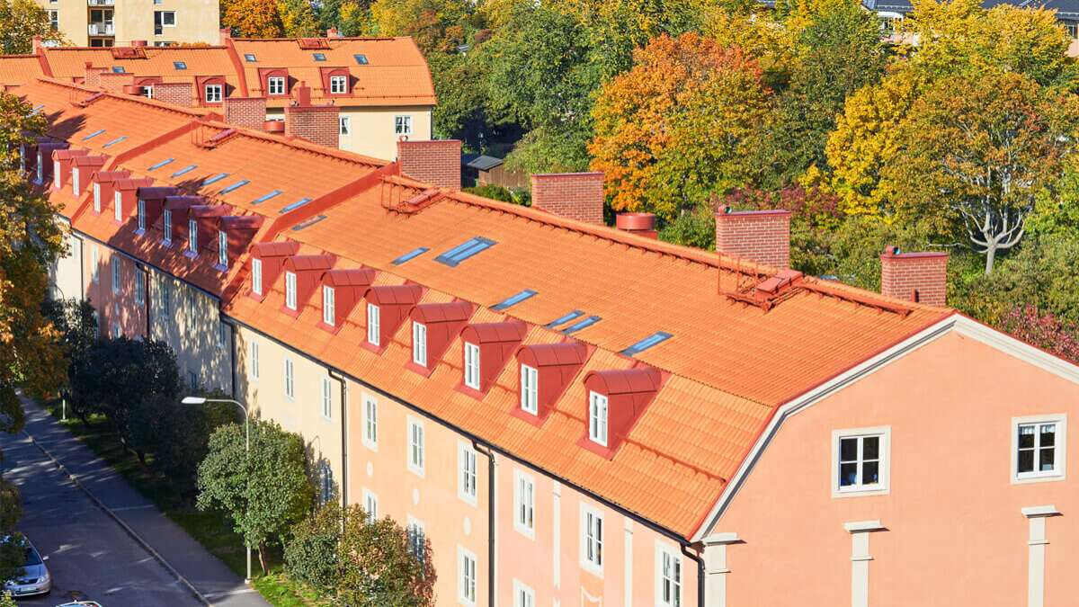 Ett laxrosa hus med tegeltak och träd i bakgrunden
